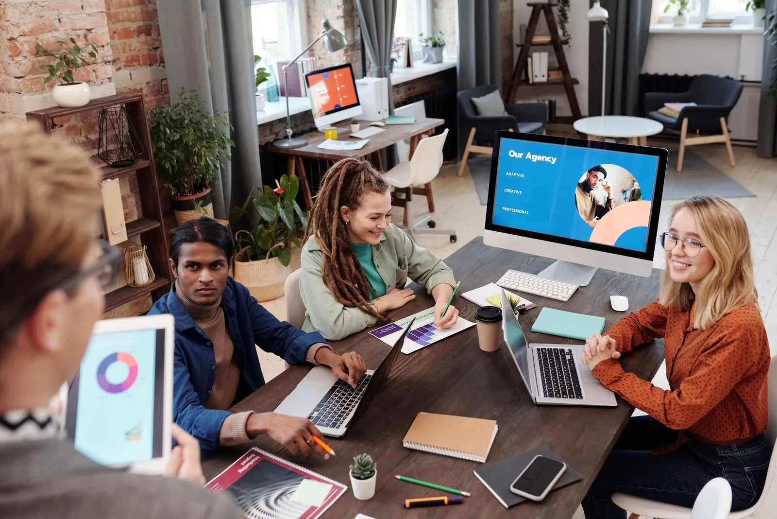 Team of diverse colleagues collaborating on project in modern office with digital devices and charts. Talent management agency expansion beyond the obvious