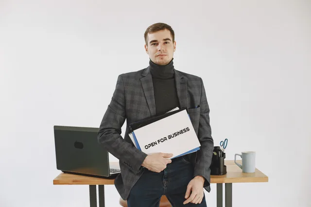 Businessman in corporate attire holding open for business sign, ready to work. Talent management agency startup costs, reviewed without the sales pitch